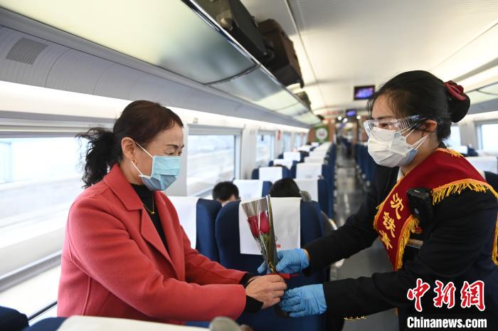 高铁乘务员将鲜花送给乘车的女性旅客。　于海洋 摄