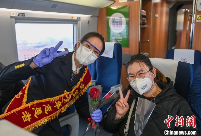 高铁乘务员将鲜花和精美小礼物送给乘车的女旅客并合影。　于海洋 摄
